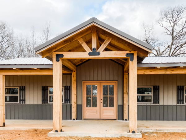 barndominium in grey and tan with wooden tresses
