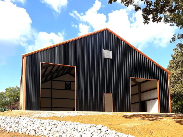 Black siding garage with orange triming, gutters and roof