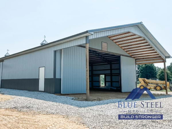 two tone grey garage with large sliding door for farm machinery sitting on a gravel area