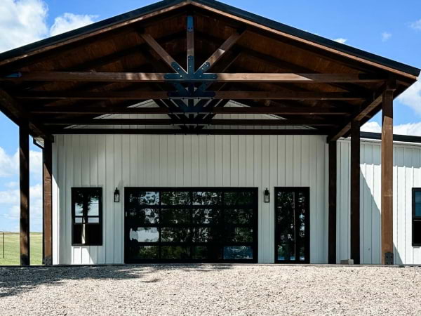 white board and batten siding with wooden tresses and black windows and doors
