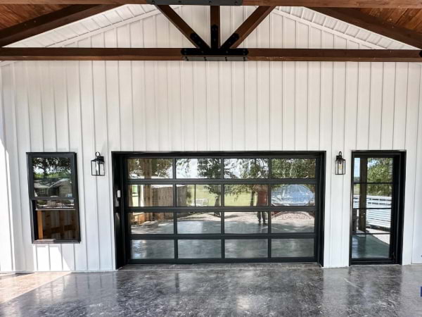 white board and batten siding with wooden tresses and black windows and doors