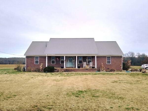 red brick house in a flat land with a brown metal roof from blue steel manufacturing