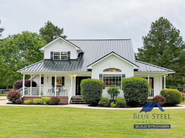 white house with beautiful landscape and a black metal roof from blue steel manufacturing