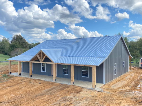 Shop home with blue siding and a blue metal roof with wooden trusses