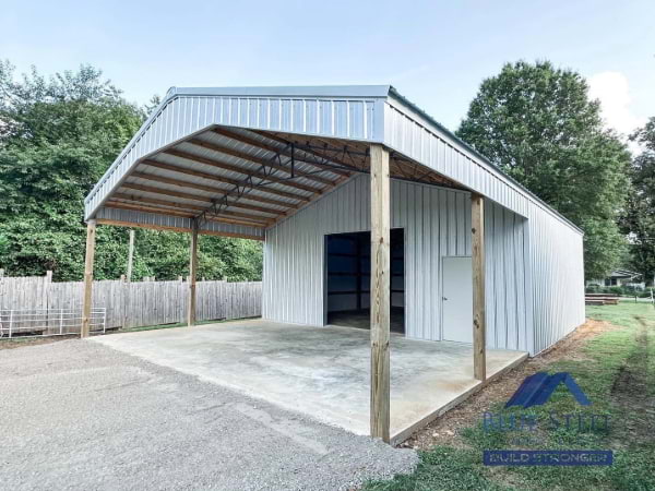 white garage with metal tress on a concrete pad and gravel in the front