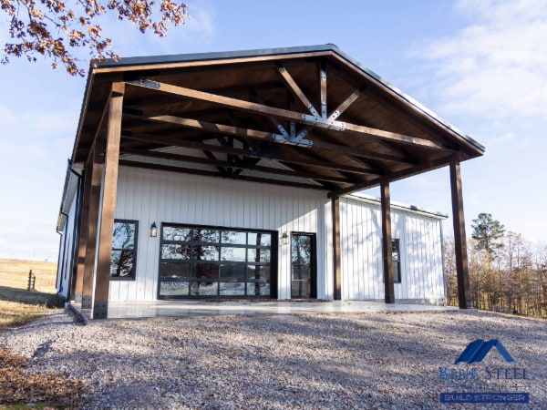 white board and batten siding with wooden tresses and black windows and doors on a gravel area