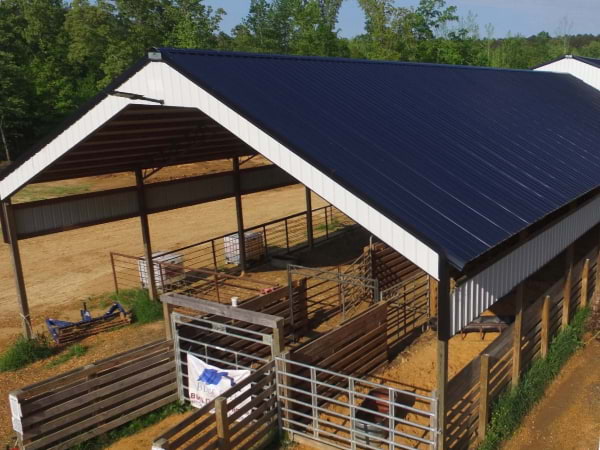 farm animal cover with open siding a black metal roof and white accents covering animal pens below