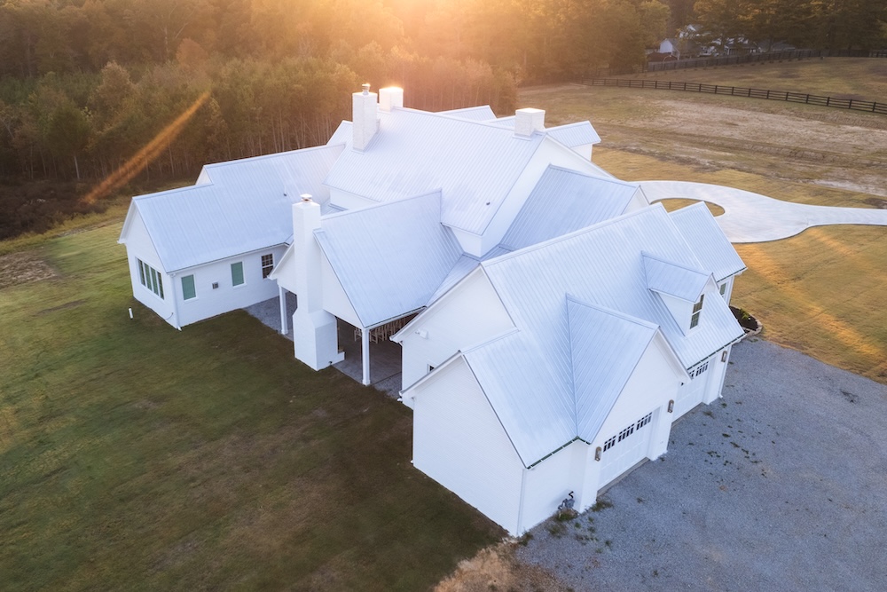 ariel view of a house built by blue steel manufactuirng with white batten siding and a light grey roof