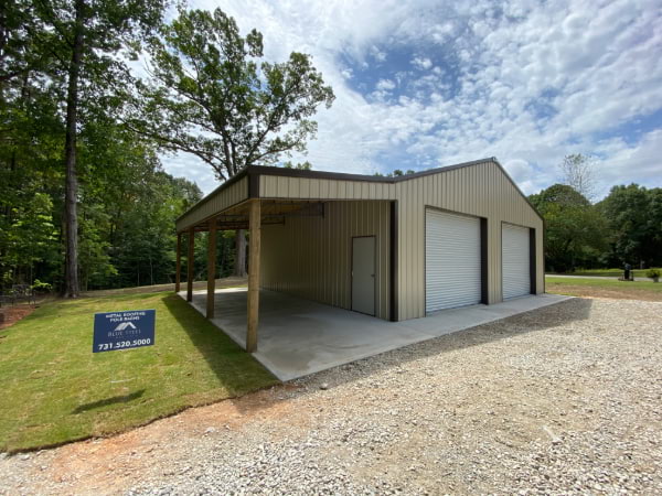 Blue Steel Manufacturing tan post frame building garage with two garage doors and lean-to
